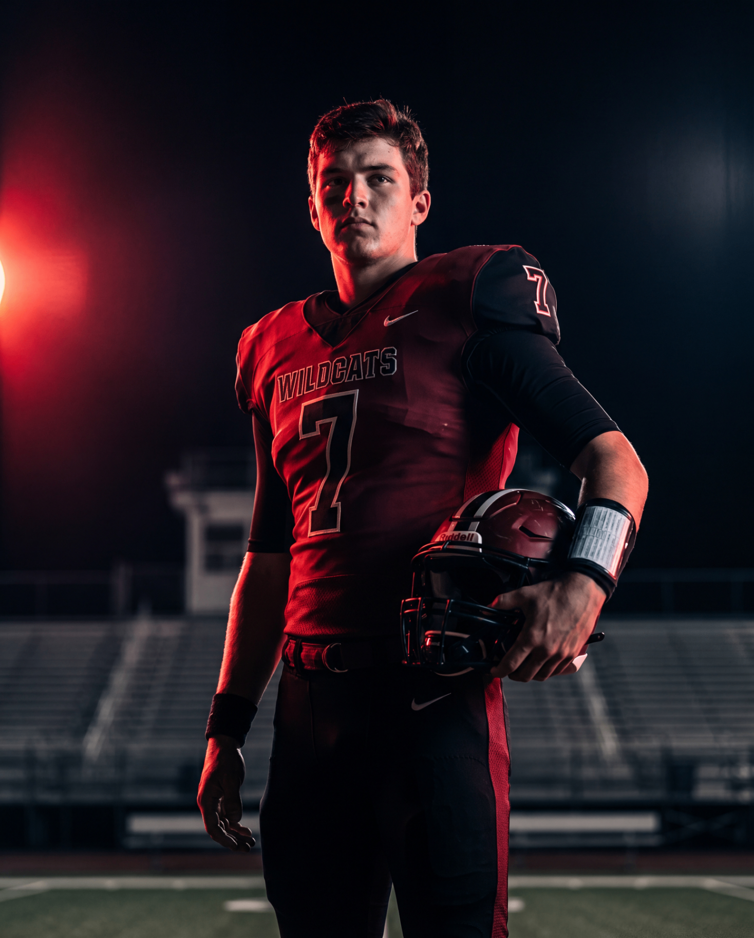 Football player in red Wildcats jersey holding helmet